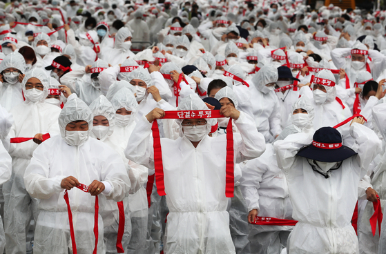 Wearing their protective gear, members of the national medical workers’ union, under the Korean Confederation of Trade Unions, stage a rally in front of the Health Ministry in Sejong on Wednesday to demand better working conditions and more medical workers to fight against Covid-19 in more efficient ways. [YONHAP]