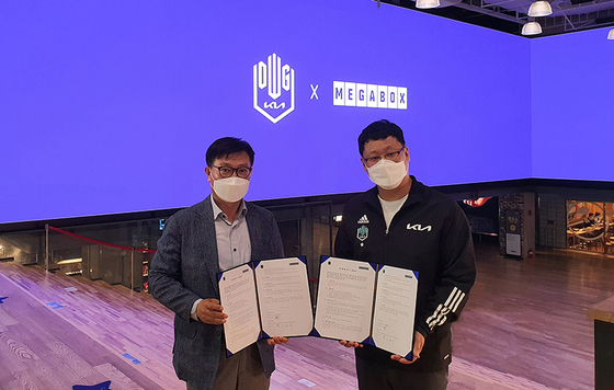 Kim Hyun-soo (left), director of Megabox's multiplex division, and DWG KIA owner Lee Yu-young pose for the cameras with copies of the memorandum in hand. [MEGABOX]