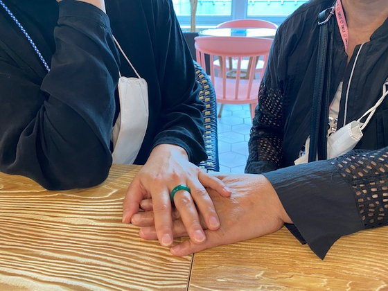 Sun Hee Engelstoft, a Korean-Danish filmmaker and Korean adoptee to a Danish family, holds hands with a woman surnamed Lee, who is looking for her adopted daughter, in a cafe in Daegu on June 24. [NATIONAL CENTER FOR THE RIGHT OF THE CHILD] 