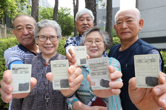 Vaccinated elderly people, sporting maskless faces, show their ID cards with inoculation stickers in Seoul on Monday, as the country began to issue the stickers to vaccinated people for mask-free activities. The vaccination certification is also available in a paper document or digitally on the COOV app. [YONHAP]