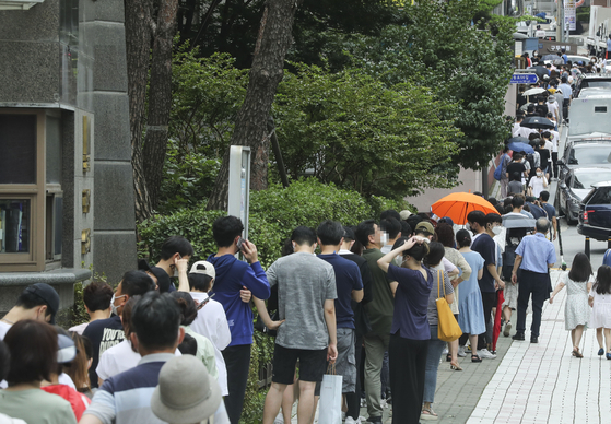 People wait in long lines to get tested for Covid-19 in Gangnam District, southern Seoul, after the country reported its second-largest daily number of new virus cases. [KIM SEONG-RYONG]