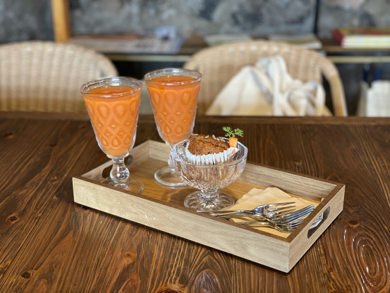 Carrot juice and a cupcake are served at Carrot and Ggannip (Carrot and Perilla Leaf). [LEE SUN-MIN]