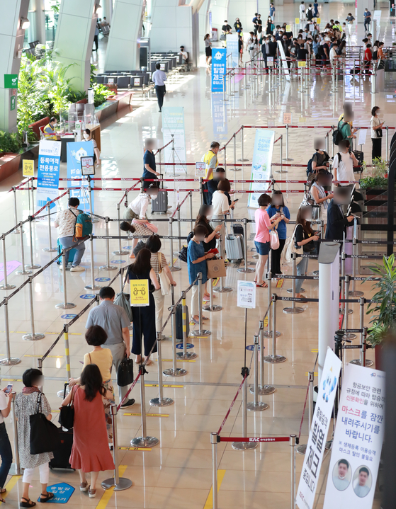 Travelers wait in line at the Gimpo International Airport on Thursday. According to data from the Ministry of Land, Infrastructure and Transport on Thursday, the number of travelers in the first half of the year declined by 29.3 percent on-year to 16.67 million people. The number of travelers using domestic flights, however, increased by 45.8 percent to 15.48 million people over the same period. [YONHAP]