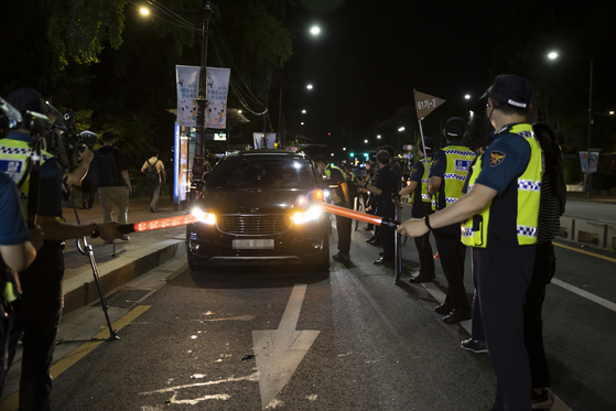 Police stop a car on a road near Marronier Park in central Seoul Wednesday night ahead of a planned drive-through rally by small business owners. [YONHAP]