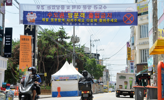 A banner at a food market in Dujeong-dong in Cheonan, South Chungcheong, prohibits the entry of visitors from the Seoul metropolitan area Friday amid concerns over a spike of Covid-19 cases nationwide. It urges people from Seoul to abide by the government's social distancing measures and come back another time. Social distancing measures are more lax in regions outside of the capital area, leading some people living in Seoul to visit in order to avoid restrictions. [KIM SEONG-TAE]