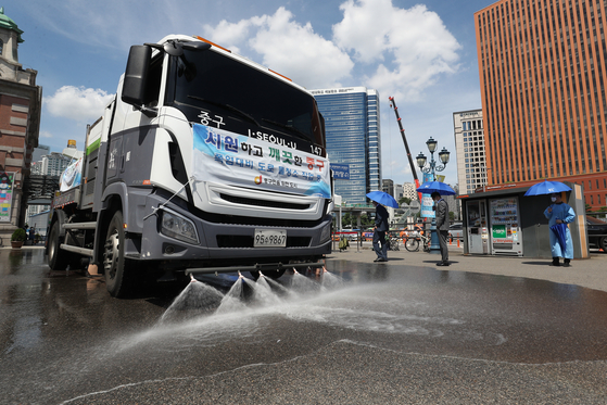 Water trucks spray a street near Seoul Station to cool it off as temperatures exceeded 36 degrees Celsius (96.8 Fahrenheit) in Seoul on Wednesday.  [NEWS1]