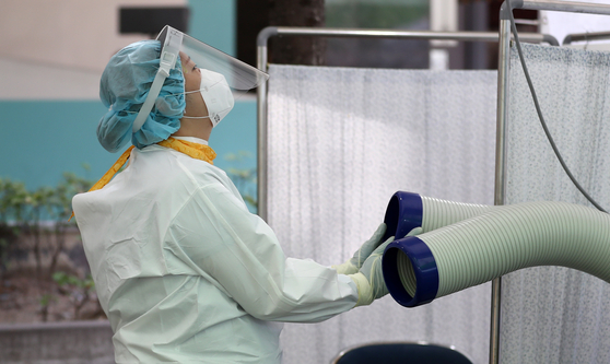 A medical worker uses an outdoor air cooler to beat the heat at a Covid-19 testing site in Daegu on Wednesday. [YONHAP]