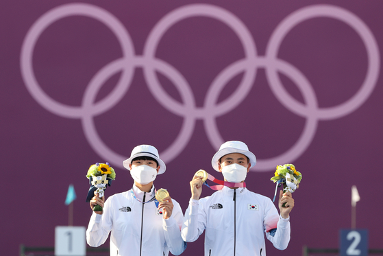 An San, left, and Kim Je-deok hold up their archery mixed team gold medals on the podium on Saturday at Yumenoshima Park Archery Field in Tokyo. [NEWS1]