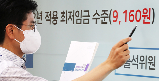 An official looks at a digital screen displaying that next year's minimum wage will be set at 9,160 won ($7.95) at the government complex in Sejong. [YONHAP]