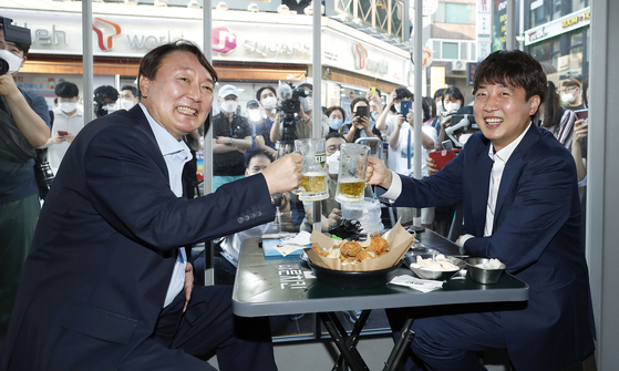 People Power Party Chairman Lee Jun-seok, right, and former Prosecutor General Yoon Seok-youl raise their glasses at a bar in Seoul on Sunday. [NEWS1]