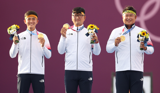 From left, Kim Je-deok, Kim Woo-jin and Oh Jin-hyek hold up their archery men's team gold medals on the podium on Monday at Yumenoshima Park Archery Field in Tokyo. [YONHAP]