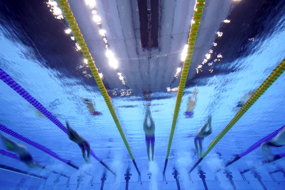 Swimmers compete in a men's 200-meter backstroke heat at the 2020 Summer Olympics on Wednesday evening. [AP/YONHAP]