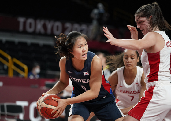 Park Ji-hyun passes around Canada's Bridget Carleton during a women's basketball preliminary round game at the 2020 Summer Olympics, held in Saitama, Japan on Thursday. [AP/YONHAP]