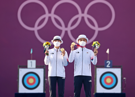 An San, left, and Kim Je-deok hold up their archery mixed team gold medals on the podium on July 24 at Yumenoshima Park Archery Field in Tokyo. [YONHAP]
