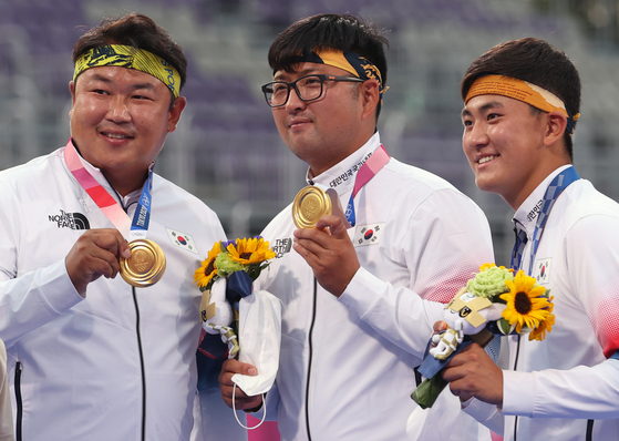 From left, Oh Jin-hyek, Kim Woo-jin and Kim Je-deok hold up their archery men's team gold medals on the podium on July 26 at Yumenoshima Park Archery Field in Tokyo. [YONHAP]