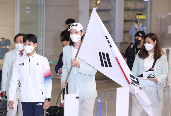 Kim Yeon-koung, center, arrives at Incheon International Airport in Incheon on Monday carrying the Korean flag alongside modern pentathlon bronze medalist Jun Woong-tae, left. [YONHAP]