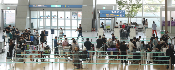 Passengers line up at Incheon International Airport to board U.S.-bound flights on Wednesday, despite the high number of Covid-19 cases. According to the Korea Disease Control and Prevention Agency, Korea's daily Covid-19 infections hit a record 2,223 on Wednesday. [YONHAP] 