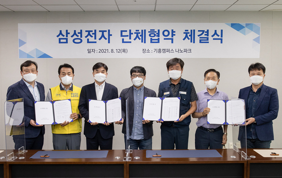Representatives of Samsung Electronics and labor unions pose for photos after signing the company's first-ever collective agreement on Thursday at Yongin, Gyeonggi. [SAMSUNG ELECTRONICS]