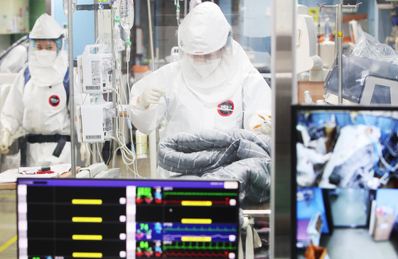 Medical staff at Bagae Hospital, a Covid-19 designated hospital in Pyeongtaek, Gyeonggi, treat Covid-19 patients while in their protective gear on Thursday. [YONHAP]
