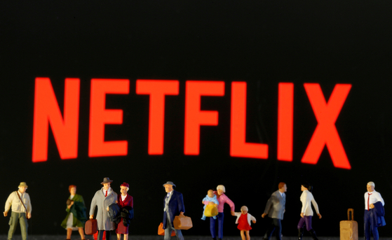 Small toy figures are seen in front of diplayed Netflix logo in this illustration taken March 19, 2020. [REUTERS/YONHAP]