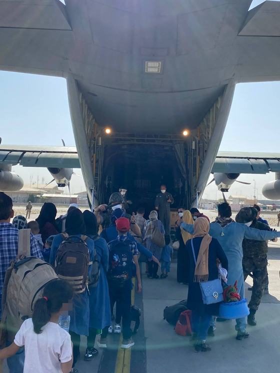 Afghans bound for Korea board a Korean Air Force transport plane at the Kabul airport Tuesday, local time. The Korean government flew three military aircraft to Pakistan earlier this week to airlift 390 Afghan evacuees, including 100 children. [FOREIGN MINISTRY]