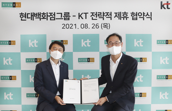 Park Jong-ook (left), head of the corporate planning group at KT, and Hyundai Department Store's co-CEO Chang Ho-jin pose for photos on Thursday after signing a business agreement at KT's Gwanghawmun Building East in central Seoul. [KT]