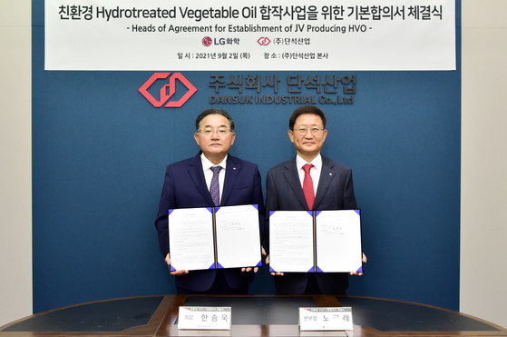 Noh Kug-lae, right, head of LG Chem's petrochemical business, and Han Seung-uk, chairman of Dansuk Industrial, pose for a photo after signing an agreement in principle to form a joint venture to build a plant that produces hydrotreated vegetable oil at the biodiesel maker's headquarters in Siheung, Gyeonggi, on Thursday. [LG CHEM] 
