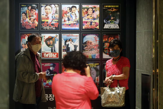Visitors to Seoul Cinema on the day of its closure take pictures in front of a photo wall displaying posters of some of the hit movies it had screened over the past 42 years. [YONHAP]