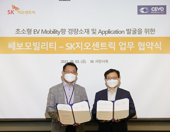 Bae Sung-chan, left, head of automotive business of SK Geo Centric, and Kwak Yong-seon, an executive from Cevo Mobility, pose for a photo after signing an agreement to cooperate on developing lightweight materials for electric vehicles in SK Group's headquarters in Jongno District, central Seoul on Friday. [SK GEO CENTRIC] 