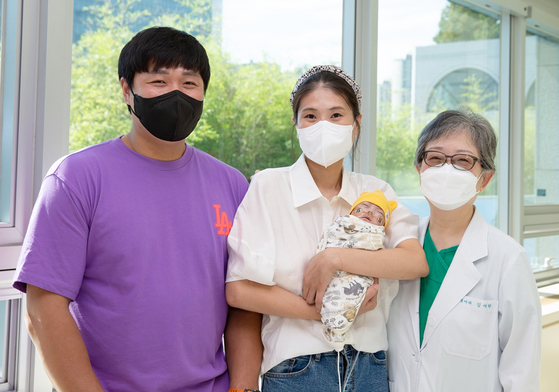 Asan Medical Center's Prof. Kim Ellen Ai-rhan, far right, and the parents of baby Gun-woo pose for a picture at the medical center in southern Seoul on Monday. Gun-woo, the smallest premature baby to survive in Korea, was discharged from the hospital after five months of intensive care. [ASAN MEDICAL CENTER]