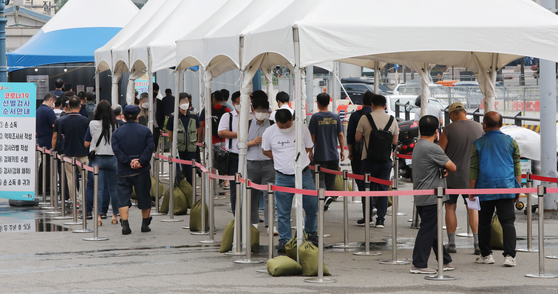 People stand in a long line at a temporary Covid-19 screening center near Seoul Station on Friday. [NEWS1]