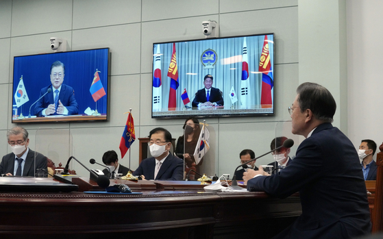 President Moon Jae-in, right, holds a virtual summit with Mongolian President Ukhnaagiin Khurelsukh at the Blue House in central Seoul on Friday as the two countries upgraded bilateral relations to a strategic partnership. [JOINT PRESS CORPS]