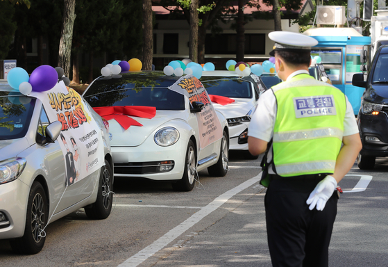 Members of the Federation of Korean Newlyweds hold a wedding car protest at the public parking lot of Yeouido Park, western Seoul, on Wednesday. Claiming that newlyweds experienced significant financial losses due to the constantly changing social distancing regulations to curb the Covid-19 spread, the betrothed couples in the federation demanded the easing of the government's restrictions on weddings. [YONHAP]