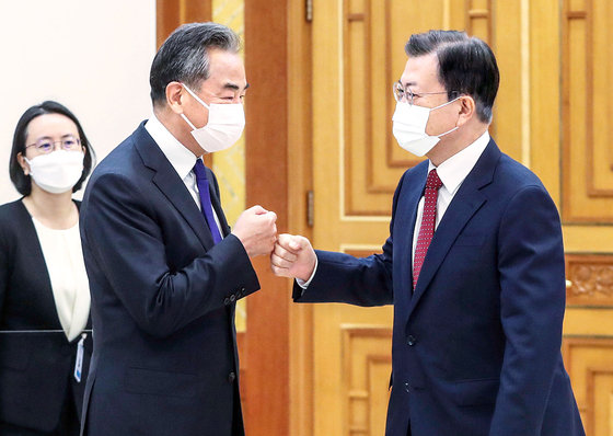 President Moon Jae-in, right, bumps fists with Chinese Foreign Wang Yi at the Blue House in central Seoul Wednesday. [JOINT PRESS CORPS] 