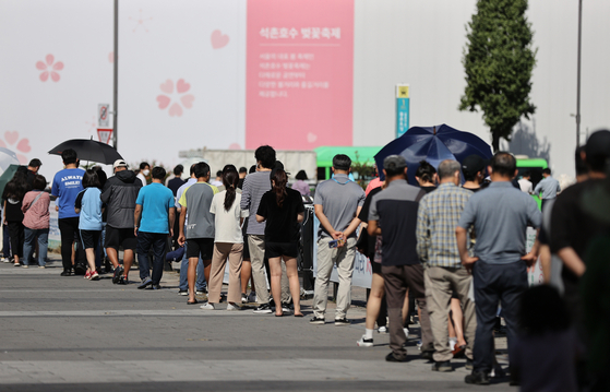 People wait in line to receive virus tests at a Covid-19 testing center at Olympic park in Songpa District, western Seoul, on Wednesday. [YONHAP]