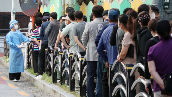 People including foreign workers line up at a Covid-19 testing clinic at a public health center in Guro District, western Seoul, on Thursday. The government plans to install temporary inoculation centers in areas with a population of 20 or more foreigners and the dispatch of medical workers to places where there are five or more foreign nationals needing inoculation in a bid to overcome hesitation by migrant workers to get the shots. [NEWS1]