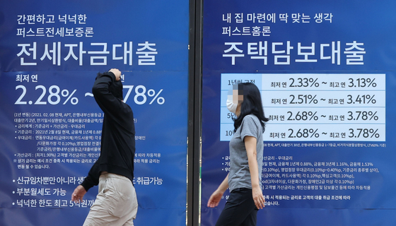 People walk past loan advertisements displayed on the wall of a bank in Seoul. Over the past month, loan rates at major commercial banks in the country rose by nearly 0.4 percentage points as the government pressures banks to curb household debt growth. The government is likely to announce a set of new regulations to tighten loans later this month. [YONHAP]