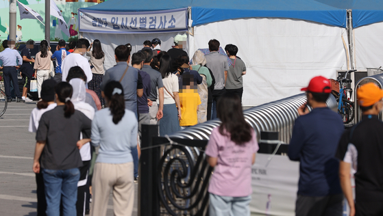 People wait to get tested for Covid-19 at a temporary screening center installed at Olympic Park in southern Seoul on Friday. [YONHAP]