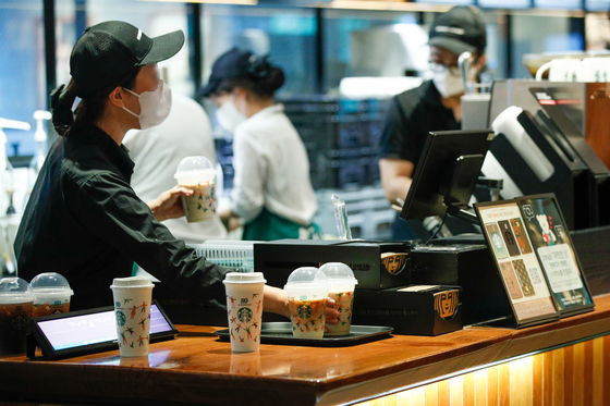 A Starbucks barista hands out orders to customers on Sept. 28 during the reusable cup day event. A free reusable cup was given with every order, and customers flooded coffee shops to get the free cups. [NEWS1]