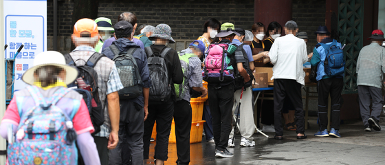 Senior citizens living alone waits in line for free lunch at a park in Jongno in August. According to Statistics Korea, among those aged over 64, there are 1.66 million that lives alone. That's 35 percent of all senior citizen households. [YONHAP]