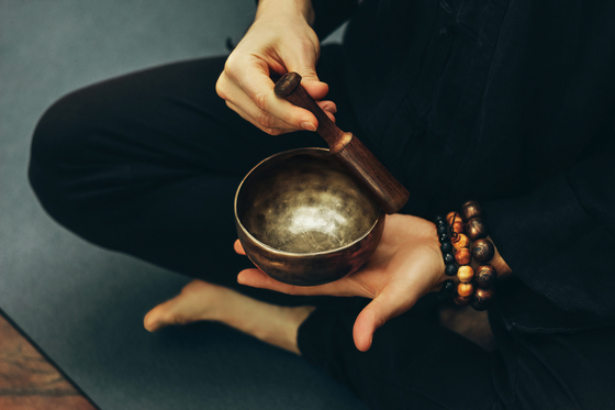 A person plays a singing bowl, an instrument used during a sound bath session that facilitates meditation. [SHUTTERSTOCK] 
