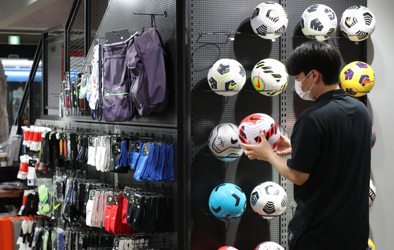 A customer picks up a soccer ball at a store in Jung District, central Seoul, on Sunday. Although the number of people newly infected with Covid-19 each day continues to remain around 2,000, sales of sports good have increased as many are expecting the government to relax its social distancing regulations. Major retailers including Lotte Department Store and Hyundai Department Store have been holding discount events particularly on golf products. [YONHAP]