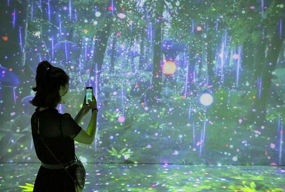 A visitor takes a photo at the "Pangyo Art Museum" exhibition at the Hyundai Department Store branch in Pangyo, Gyeonggi, on Monday. Some 50 artworks are displayed and a video of a magical forest is featured on a huge digital screen. The exhibition runs through Oct. 24. [YONHAP]