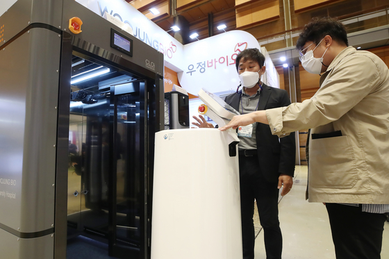 Visitors look at Woojung Bio's sterilization machine for robots that transfer and dispose medical waste at the CPhI Korea 2021 exhibition held at Coex in Gangnam District, southern Seoul, on Monday. Companies specializing in medical devices and equipment attended the event. The exhibition runs through Wednesday. [YONHAP]