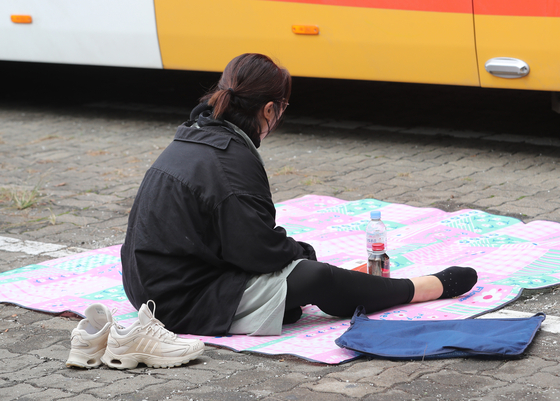A merchant looks to be lost in thought on a mat at a parking lot for the Mapo Agriculture and Marine Products Market in Mapo District, western Seoul, on Monday after the market closed down as Covid-19 infections from the market grew to 89. [NEWS1]