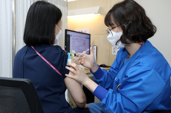 A medical staffer receives a Covid-19 booster shot on Tuesday at the National Medical Center in central Seoul. [YONHAP]