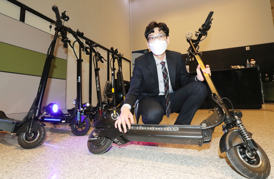 A Korea Consumer Agency official shows off an electric scooter at the government complex in Sejong on Tuesday. After testing the six most popular electric scooters, the agency reported that the Euro 8 TS600 Eco travels the longest at maximum speed. In tests, it covered 42.4 kilometers (26.34 miles) when fully charged. The Speedway Mni4 Pro trailed behind with 40.4 kilometers and the Moto Bello M13 with 38.6 kilometers. [YONHAP]