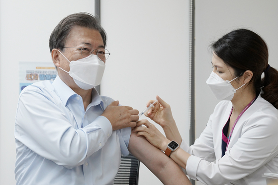 President Moon Jae-in, left, receives a Covid-19 vaccine booster shot Friday at the National Medical Center in central Seoul ahead of an overseas trip at the end of this month. [YONHAP]