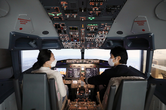 Models try a flight simulator in Hongdae, western Seoul. The service is offered by Jeju Air. [JEJU AIR]
