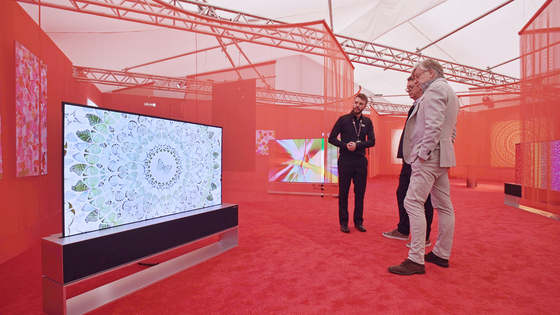 Visitors examine the works of Damien Hirst displayed on LG Electronics' Signature OLED R, a high-end organic light-emitting diode rollable television model at the Frieze London art fair. [YONHAP] 